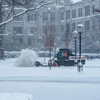 A snow plow moves through campus