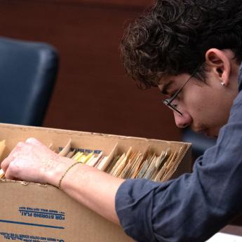 A students flips through documents in a box during anthropology class