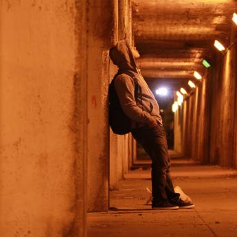 Person in hoodie standing alone in alley