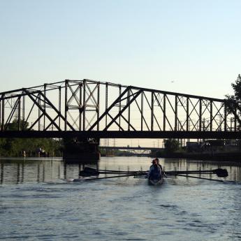 People rowing in river in front of bridge