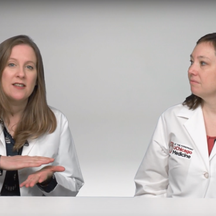 Two doctors in lab coats discuss coronavirus sitting at a table