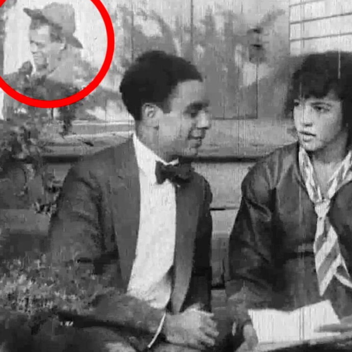 Black and white still from the film The Trooper of Troop K. A man and woman sit on a front stoop looking at each other. The woman is holding a letter. In the left-hand corner is a superimposed scene of a man in a military hat talking to a woman.