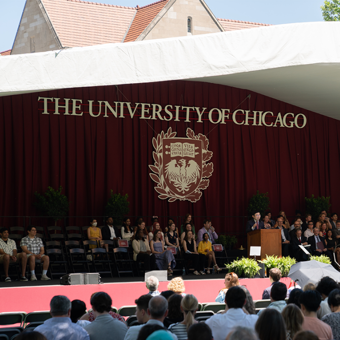 Crowd facing a stage with University of Chicago logo. A speaker stands at a podium