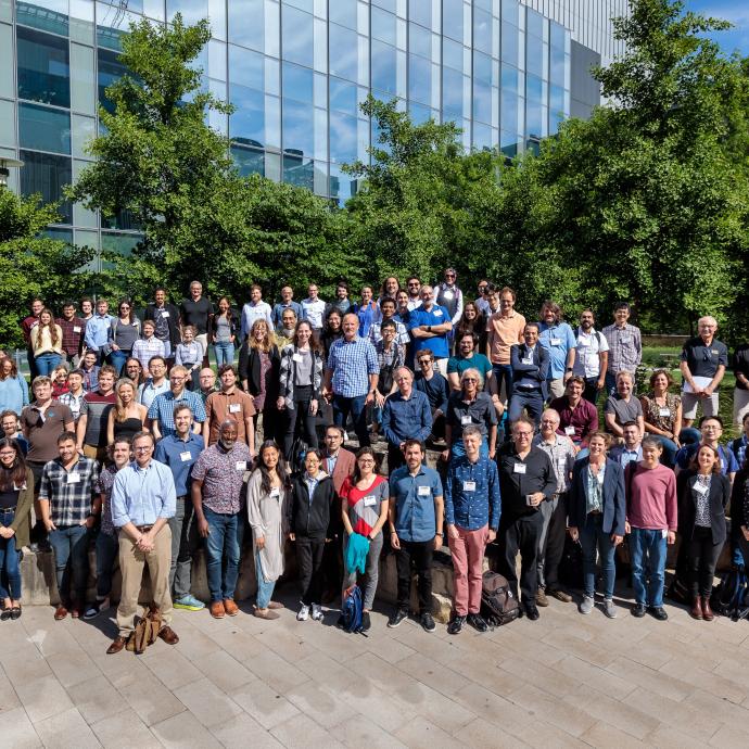 Group photo of 100+ people outside a building with many windows