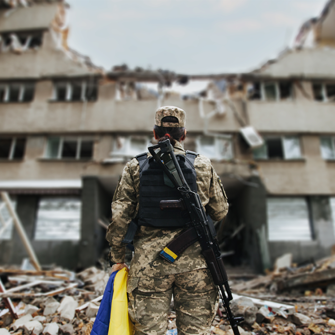 Ukrainian military woman with the Ukrainian flag in her hands on the background of an exploded house