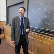 Three chemists discuss equations at blackboard