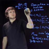Asst. Prof. Daniil Rudenko writing equations on light board
