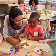 Preschool children learning math at table with teacher