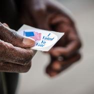 Black voter holding an "I voted" sticker