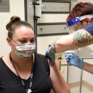 Healthcare worker gives a vaccine to seated masked woman