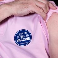 Person lifting the sleeve of their shirt to show the bandage over their covid-19 vaccination
