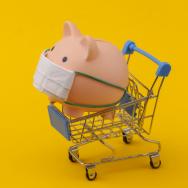 A piggy bank with a mask inside a toy shopping cart