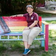 Kathy Forde sits on a rainbow-colored bench on the UChicago campus