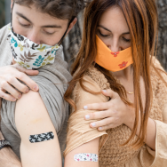 two young people compare colorful bandaids after a vaccine