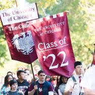 UChicago students hold Class of 2022 banners as they walk behind bagpipers