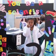 Girl poses in lab coat at science fest 