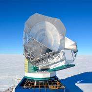 Photo in the daytime of the South Pole Telescope, a large telescope in the middle of a snowfield