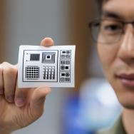 Chuanwang Yang holds up a square of paper with patterns stamped in ink