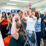 a room of scientists cheer in front of a bank of computers