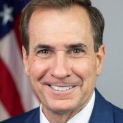 A man smiles for a headshot in front of the U.S. flag