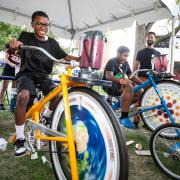 Two kids race stationary bikes at the Physics tent