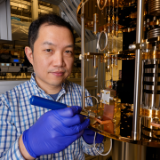 A man faces the camera while adjusting a part on quantum computer