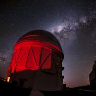 Observatory under red light with Milky Way in background